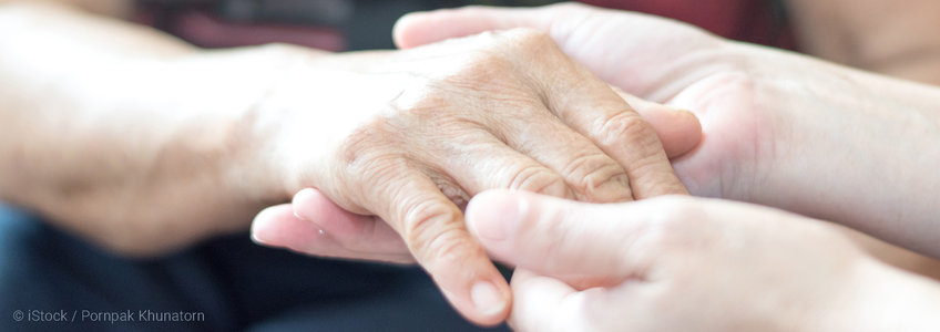 Pflegeperson hält Hand einer Person nach Schlaganfall