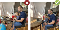 Father and child sitting at a table in front of a laptop.