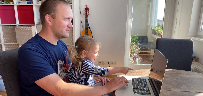 Information for parents about our online studies Young child sitting on adult's lap pointing at laptop screen.