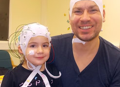 In der Studie erfassten die Wissenschaftler mithilfe des EEG (im Bild: weiße Kappe) die Hirnströme der Kinder mit Cochlea-Implantaten (im Bild links in türkis). © Niki Vavatzanidis, MPI CBS